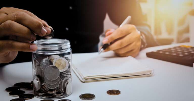 man in suit, white table, pen, coins, book, sunlight, jar of coins